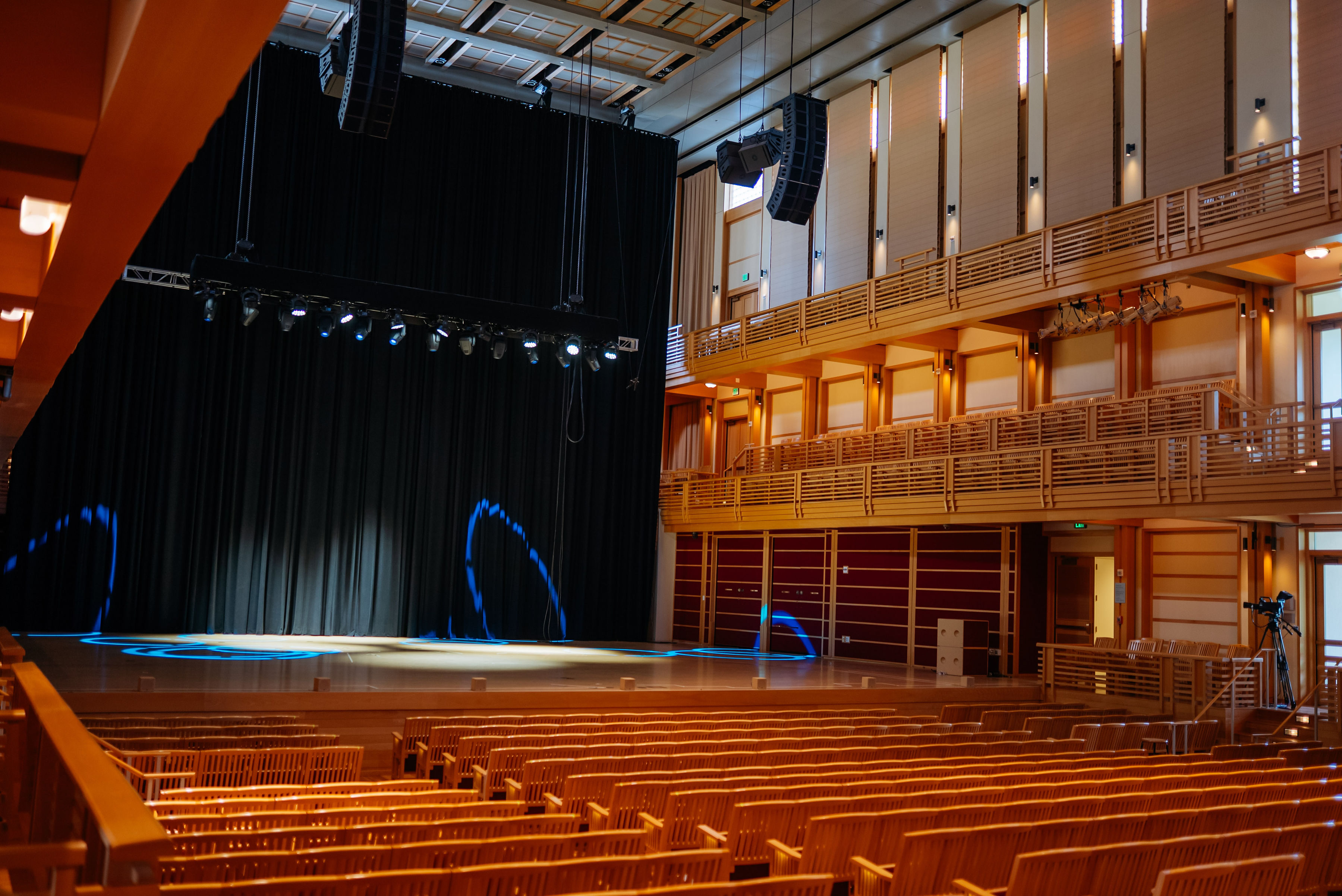 Empty wooden concert hall at the Green Music Center with tiered balconies and a stage lit by blue spotlights